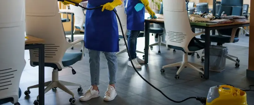 Dues persones netejant una oficina, una d'elles amb una aspiradora